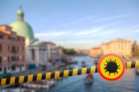 Warning sign with Coronavirus molecule on a police line on the blurred background of Grand Canal in Venice, Italy.